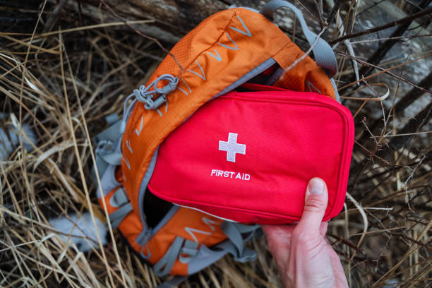istock A person is carefully holding a bright red first aid kit beside a vibrant orange backpack, showcasing the essential supplies needed for emergencies during outdoor activities 2198332338