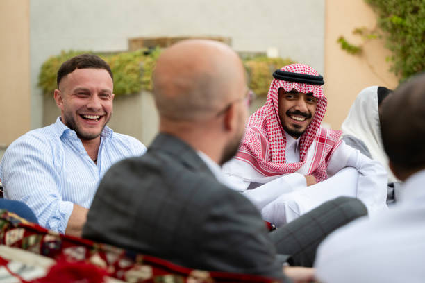 Western and Arabic businessmen discussing business deal outside in relaxed setting, enjoyment, success, happiness