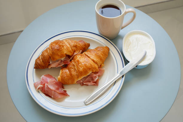 istock Home breakfast: two croissants with prosciutto, cream cheese and black coffee 2198334031