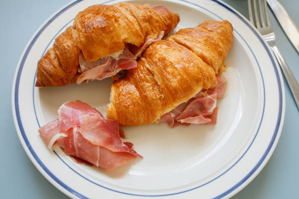 istock Two classic butter croissants with prosciutto on a plate close up 2198334038