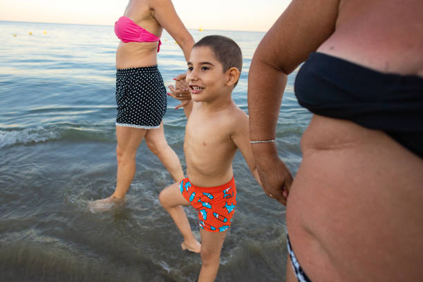 A grandmother, mother, and son with special needs share a heartfelt moment by the ocean,
