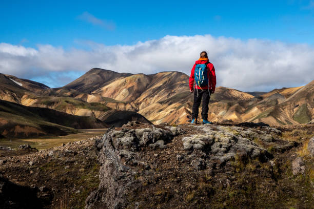 istock Adventurous man in red jacket and blue backpack hiking through stunning rainbow mountain Landmannalaugar deep inside Iceland 2198335988