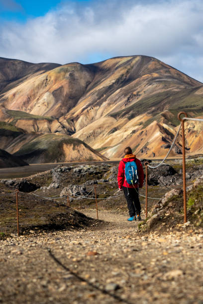 istock Adventurous man in red jacket and blue backpack hiking through stunning rainbow mountain Landmannalaugar deep inside Iceland 2198335992