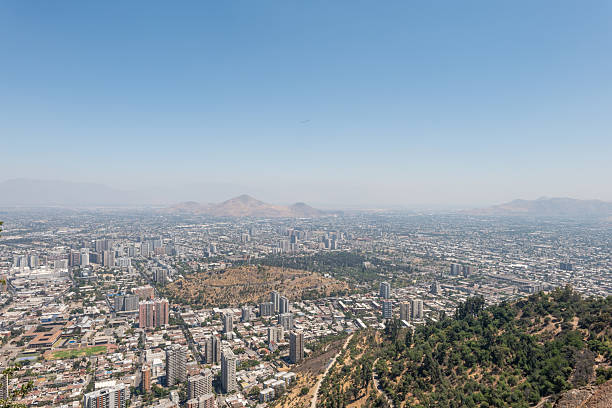 Expansive urban view with high-rise buildings under a clear sky. Cityscape showcasing downtown with scenic mountains.