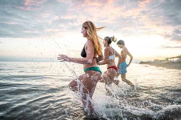 istock Three cheerful friends running into sea 2198338406