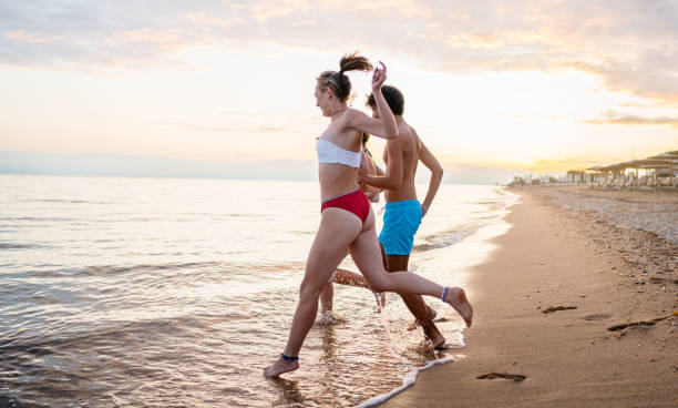 istock Happy friends running into the sea 2198338492