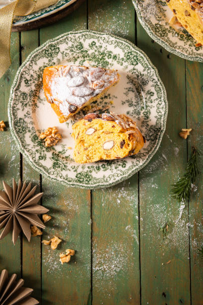 istock Festive Bolo Rainha slice on green plate, with powdered sugar, almonds & walnuts, on a green table with Christmas decor. A traditional Portuguese Christmas, New Year's & Epiphany dessert. 2198339473