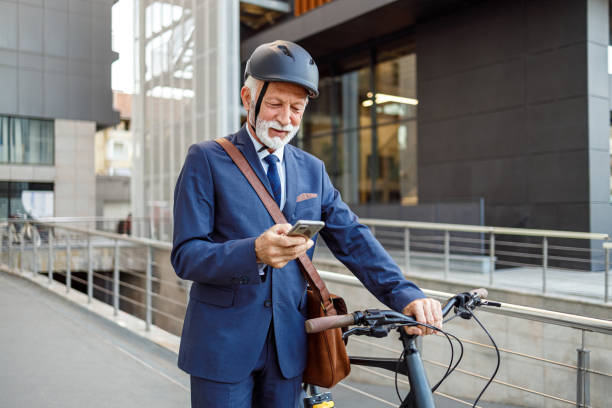 istock Male entrepreneur in helmet messaging over mobile phone and pushing his bicycle while walking in city 2198341943