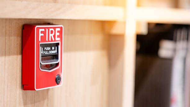 Red fire alarm switch mounted on wooden wall in the office interior. Fire warning system equipment for emergency and evacuation in public building stock photo