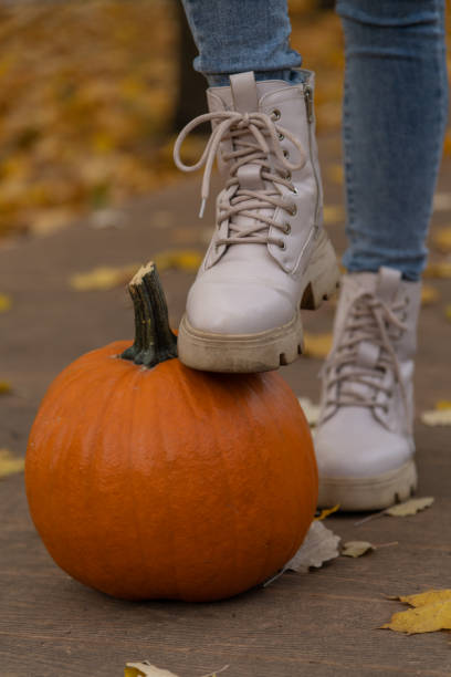 istock Woman stepping on a pumpkin during a fall celebration near leaves 2198343884