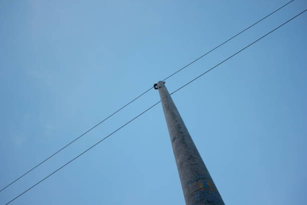 photo of low angle view of electric pole with natural sky background