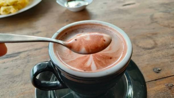 a cup of chocolate on the table. delicious warm chocolate. hot chocolate in a black cup. when the hot chocolate is on the spoon it looks very delicious.