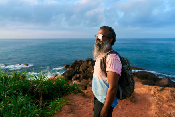 istock Senior multiethnic man hikes along scenic coastline with backpack. Elder enjoys outdoor adventure, exploring rocky shore. Retired traveler embraces nature beauty, cherishing active life outdoors. 2198356595