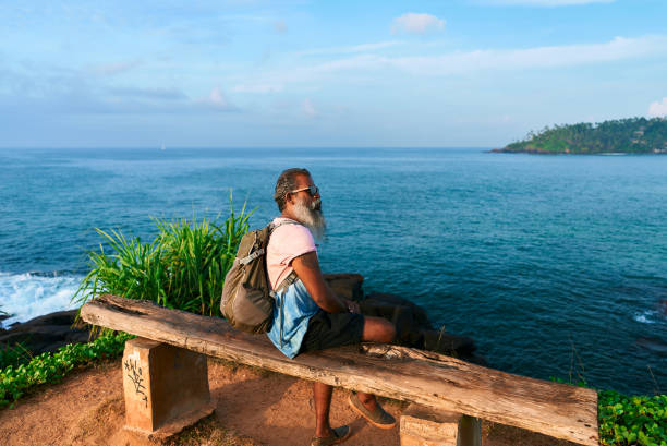 istock Bearded senior with backpack on bench by ocean. Lonely man enjoys peaceful sea view. Contemplates life journey nature therapy and healing. Embraces solitude for introspection after loss. 2198361915