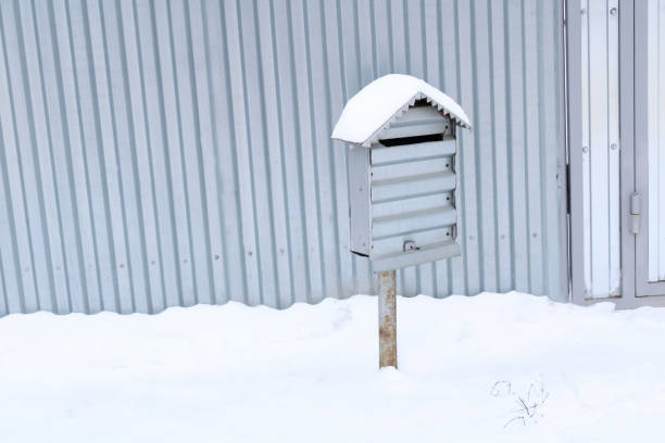 A mailbox made of metal, surrounded by snowdrifts.