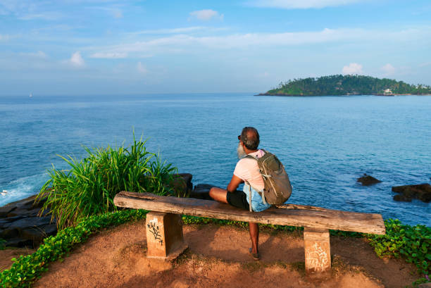 istock Lonely senior man with backpack sits on bench. Ocean view, serene solitude. Contemplates life, healing, nature therapy. Retired man introspection, mental health, emotional recovery by sea. 2198364732
