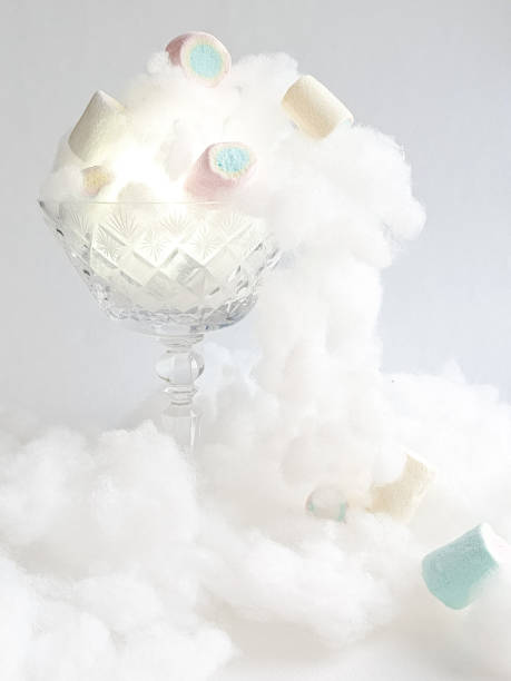 istock Marshmallows and cotton candy fall out of a glass candy bowl on a white background. Delicate, airy marshmallows and cotton candy. Promotional photo of sweets. 2198364736
