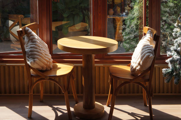 istock Cozy Wooden Dining Table With Soft Pillows in a Sunlit Cafe Setting 2198370351