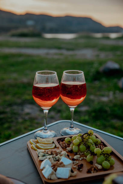 Picnic in nature with wine, cheese plate, grapes with mountains and sunset in the background. High quality photo