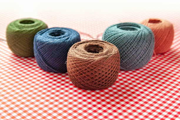 Multicolored spools of cotton thread on a red checkered background. Selective focus, space for text.