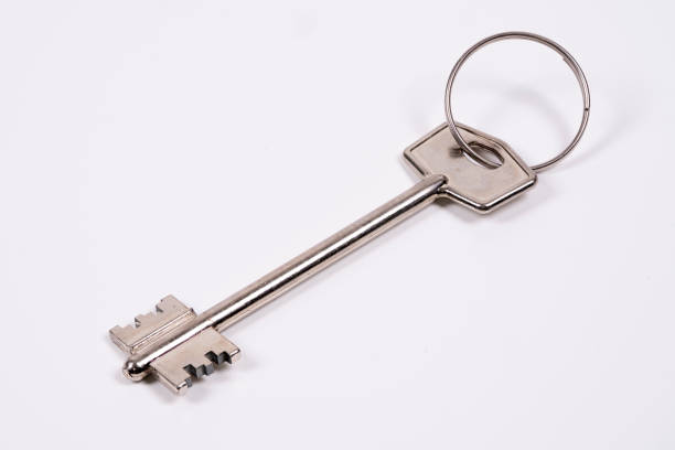 istock Large vintage key on a keyring resting on a plain background 2198378097