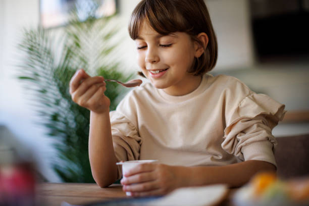 istock Cute little girl eating fruit yogurt 2198380858