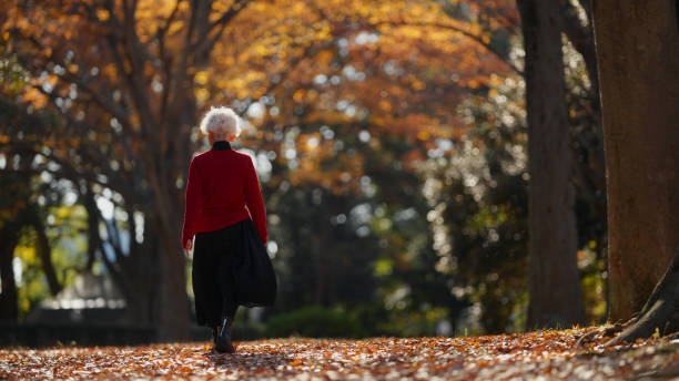 istock Senior Woman Walking Through Autumn Forest 2198381724