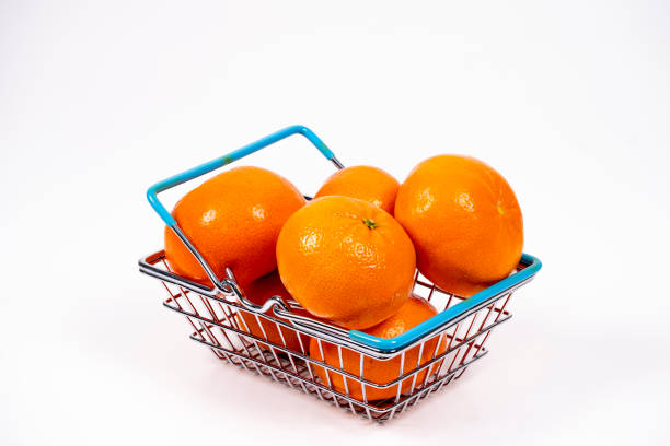 A small basket filled with vibrant oranges sits against a white background, showcasing the fruit's bright color and fresh appearance, ready for purchase.