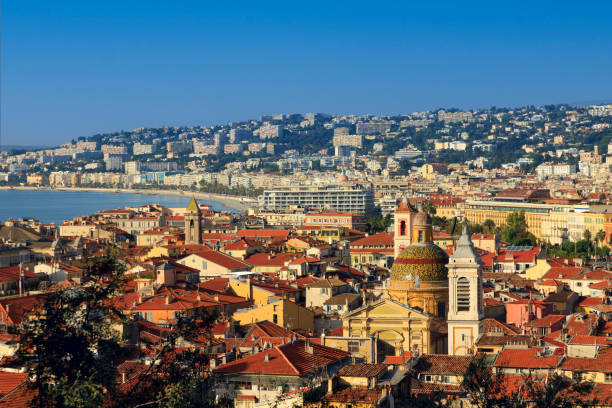 istock A stunning sunrise over Nice, showcasing vibrant red rooftops, a charming church dome, and the curving coastline against a clear blue sky 2198382564
