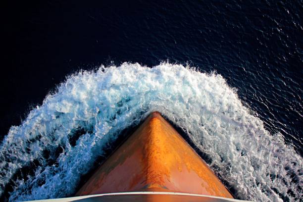 Iron red bulb of the bow of a big oil tanker is underway at sea while it sunset.