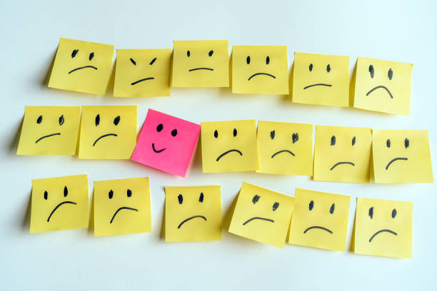 istock Pink Post-It With Smiley Among Yellow Sad Faces Symbolizing Positivity 2198386819