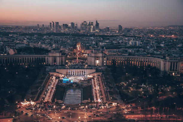 A Paris city with a large building in the center. The building is lit up at night. There are many cars on the street