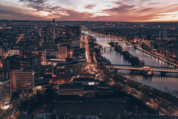 A Paris city at night with a river running through it. The city is lit up with lights. There are many cars on the road