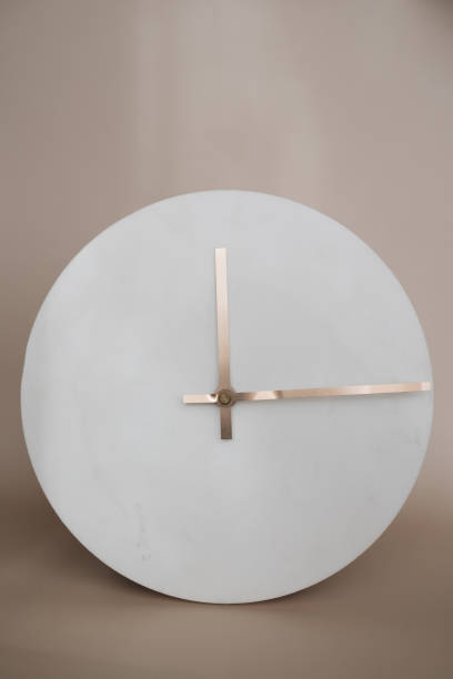 istock White Round minimalist marble wall clock with golden hands on a beige background 2198387360