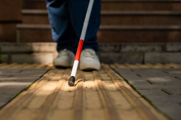 istock A blind woman walks outdoors using a cane along a tactile yellow tile. 2198392713