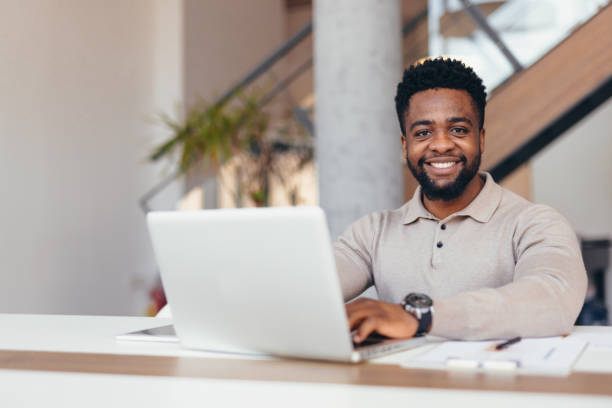 istock Young businessman smiling and working on laptop in modern office 2198392826