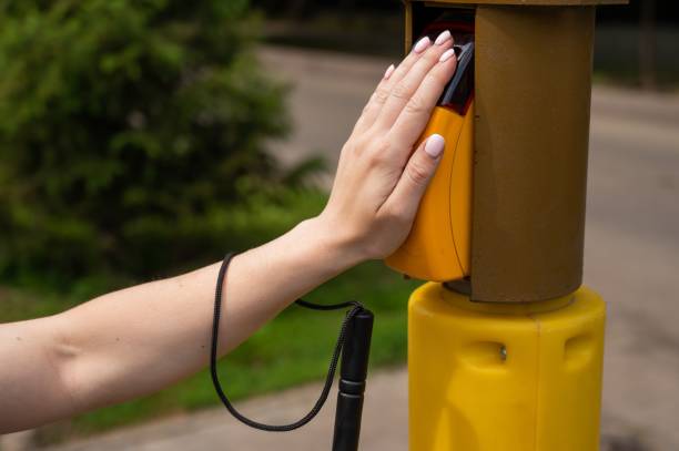 istock Close-up of a blind woman's hand pressing a button for a traffic light. 2198393539