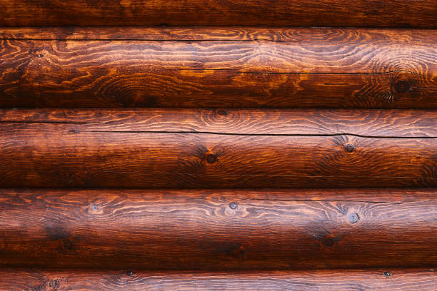 Detailed view of smooth, dark wooden logs showcasing rich textures and organic patterns in a tranquil cabin environment.