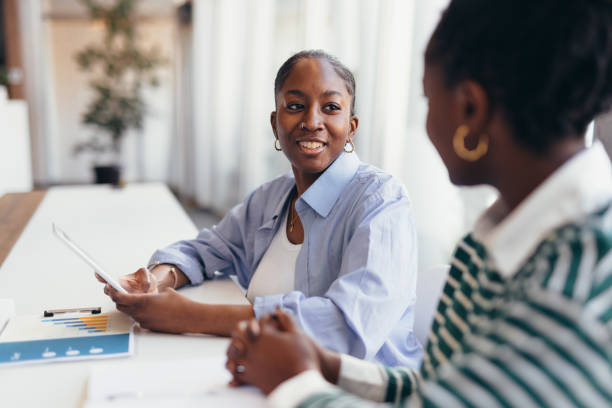 istock Two young black businesswomen discussing using a digital tablet in the office 2198395472
