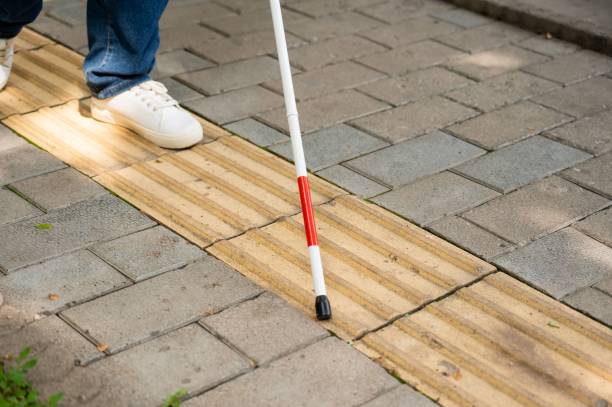 istock A blind woman walks outdoors using a cane along a tactile yellow tile. 2198396277