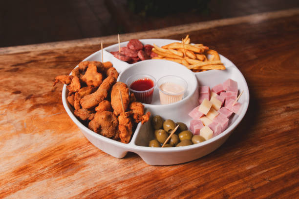 Top view of various snacks on a large tray on a wooden table.