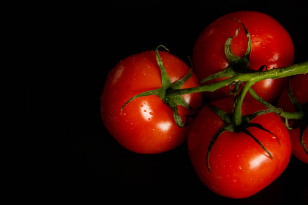 istock Slices of fresh tomatoes on black background 2198398585