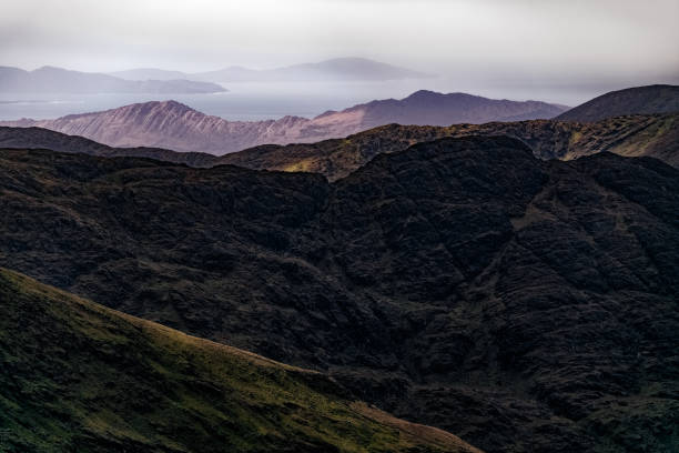 istock Misty mountain landscape with layered hills and distant coastline under cloudy sky at twilight. 2198400029