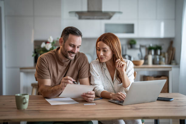 istock Loving couple working together on documents at their home office desk 2198400651