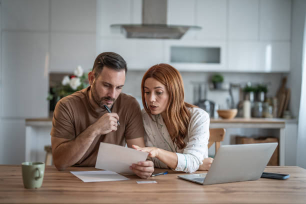istock Loving couple working together on documents at their home office desk 2198400707