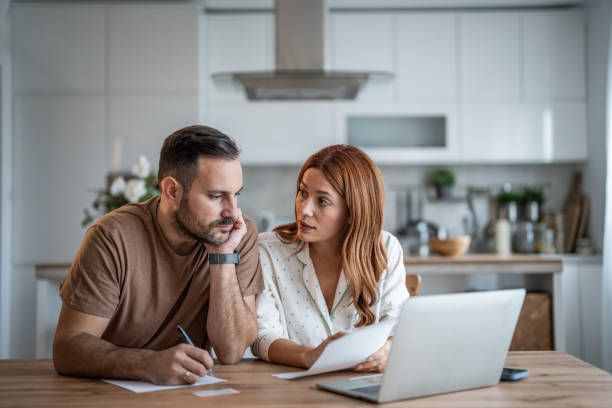istock Loving couple working together on documents at their home office desk 2198400712