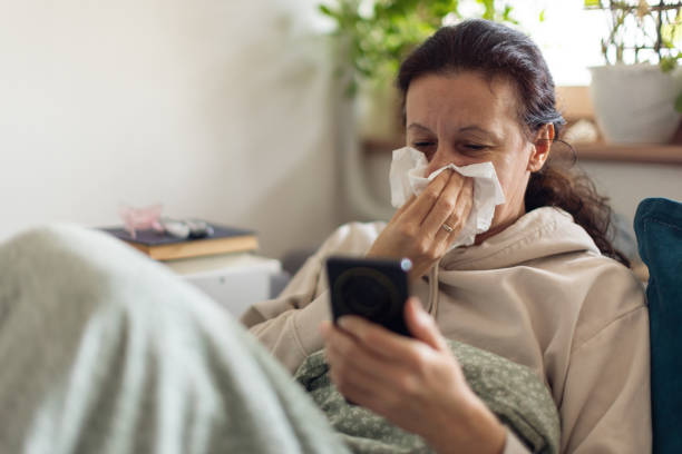 istock Woman suffering from flu at her home and using a mobile phone 2198400765