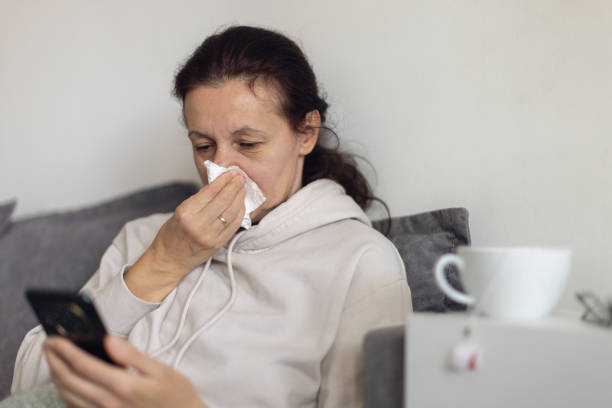 istock Woman suffering from flu at her home and using a mobile phone 2198400829