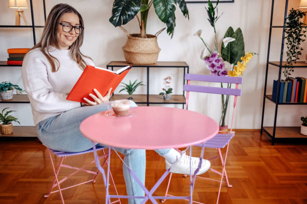 istock Young beautiful woman enjoying coffee alone at home while reading book 2198401131