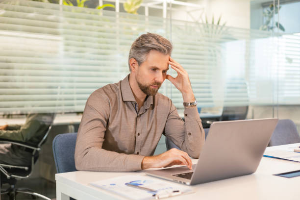 istock Serious business man working on documents looking concentrated with laptop on the table 2198401496